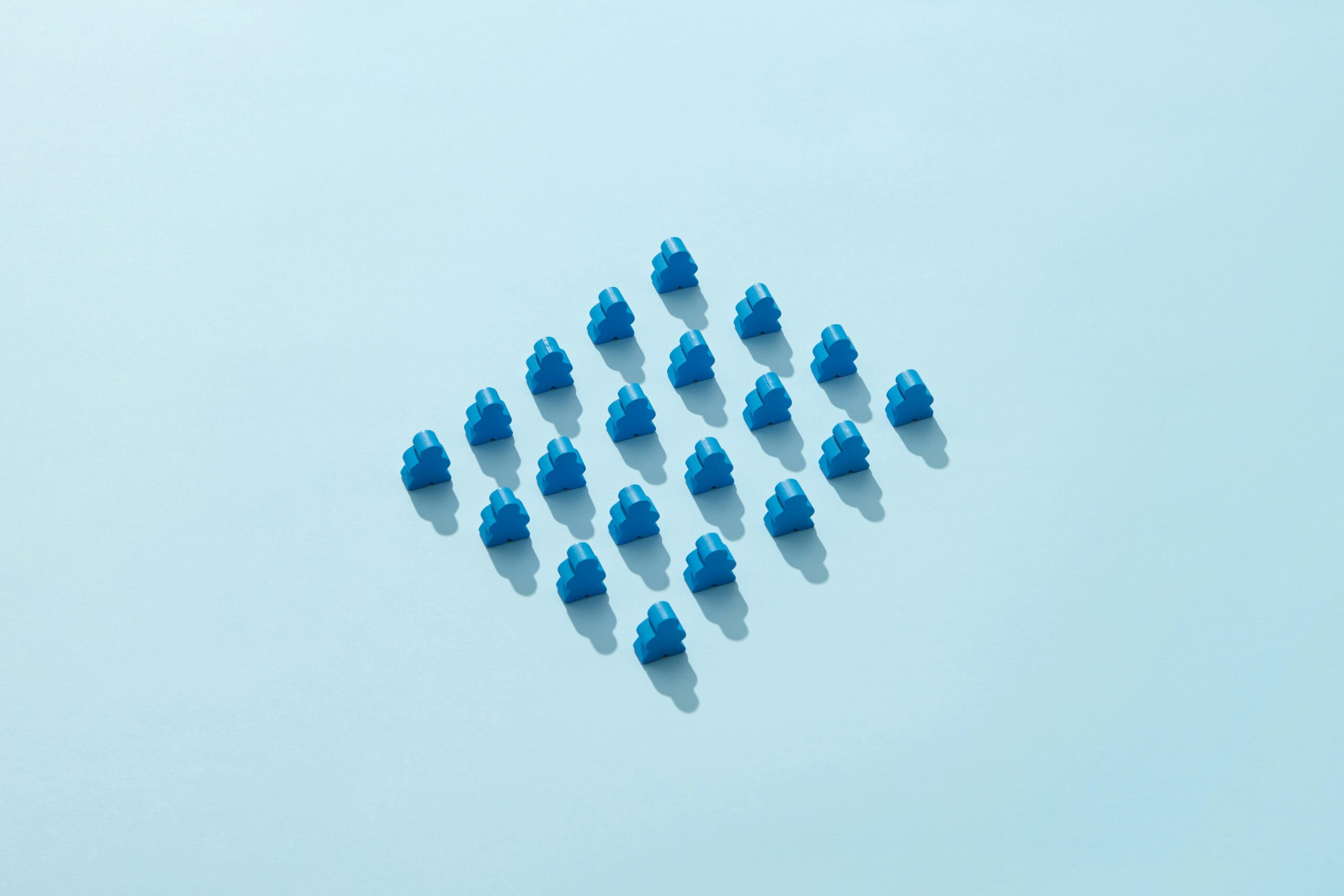 Artistic arrangement of blue meeples on a pastel blue background, highlighting patterns and symmetry.